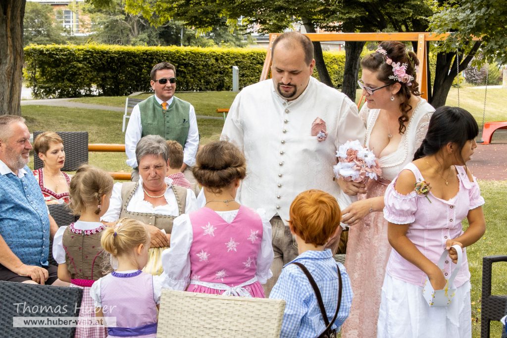 Braut und Bräutigam stehen vor mehreren Blumenkindern, die Blumen aussträuen.