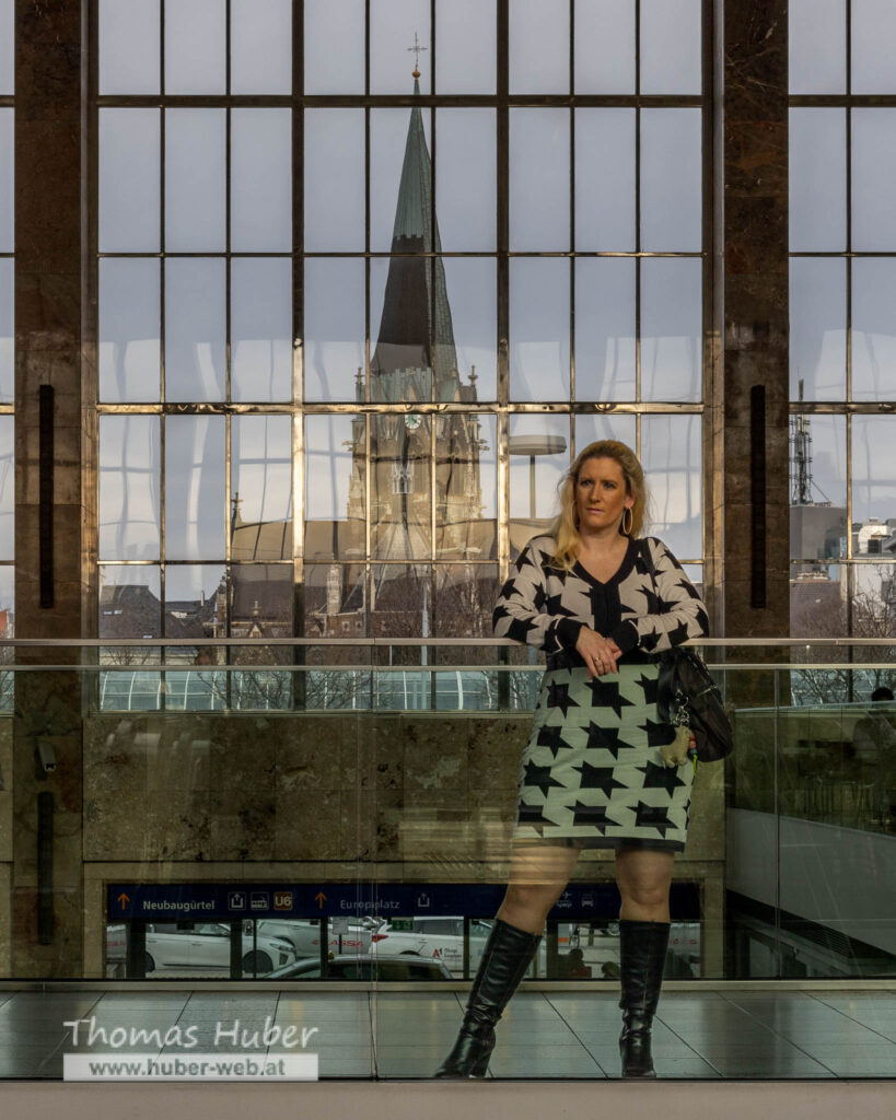 Lovely Crazy Woman steht bei Glasgeländer, großes Fenster mit Kirche im Hintergrund