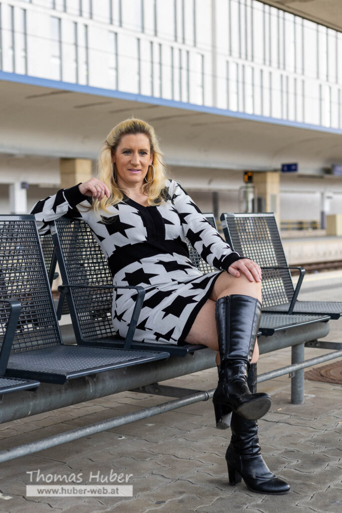 Lovely Crazy Woman sitzt auf Bank am Bahnsteig