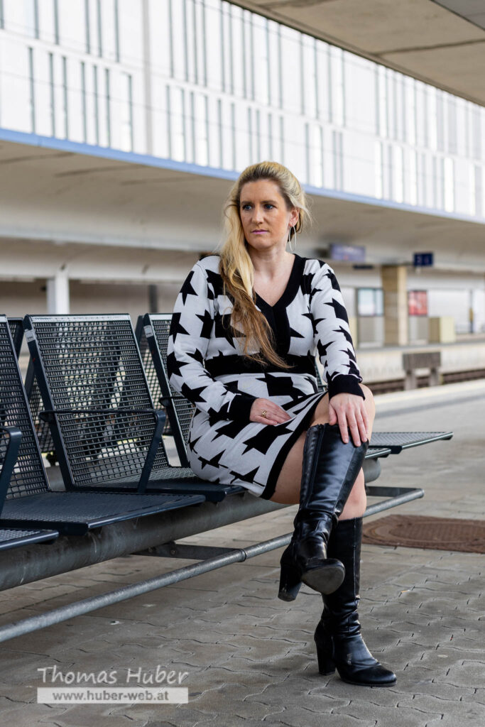 Lovely Crazy Woman sitzt auf Bank am Bahnsteig